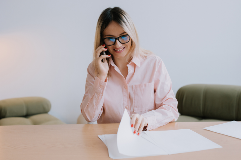 young woman on the phone looking through paper work